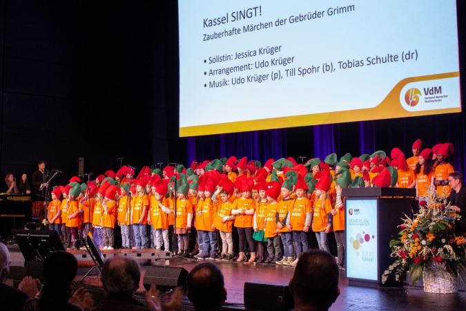 A group of children with green and red pointed caps on a stage