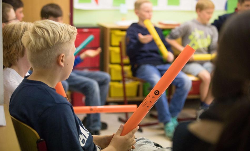 Tag der Musik an der Hochschule für Musik und Theater Rostock. Die Kinder sitzten mit Boomwhackern in einem Stuhlkreis.