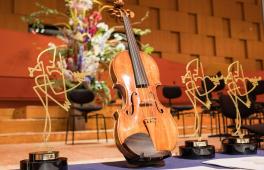 Eine Violine zwischen den Trophäen für den Joseph Joachim Violinwettbewerb 2018.