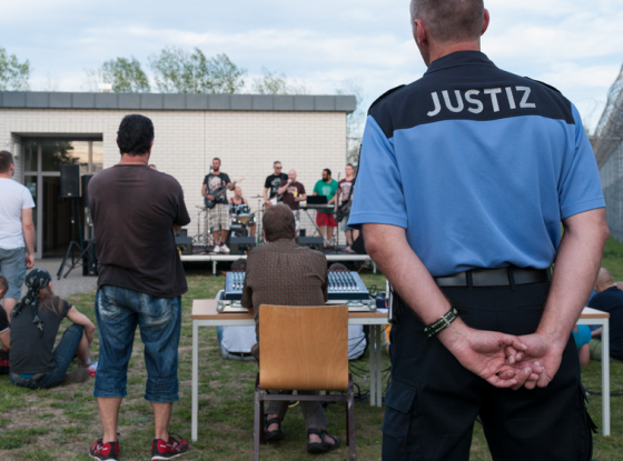 Foto eines Justizvollzugsbeamten, der einer Band zuschaut
